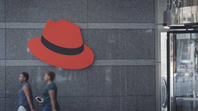 Persone che camminano con il cappello rosso sul muro.
